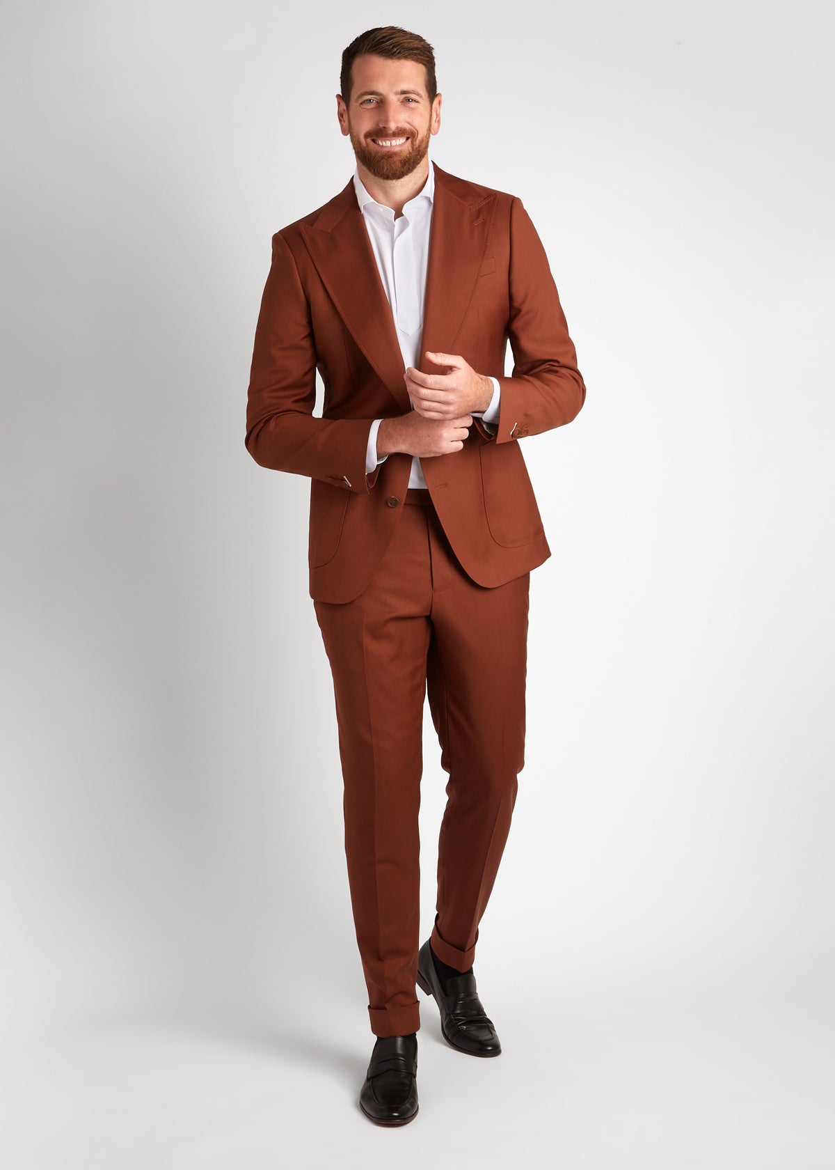 Birmingham Tobacco Brown Suit, hands clasped at the waist, broad smile, open collar
