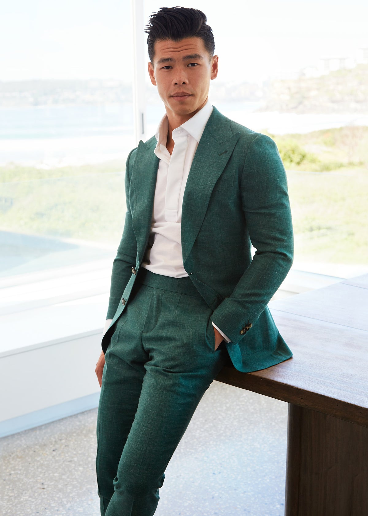 Vincent Green Linen Blend Suit worn by a model leaning against a table by a coastal window