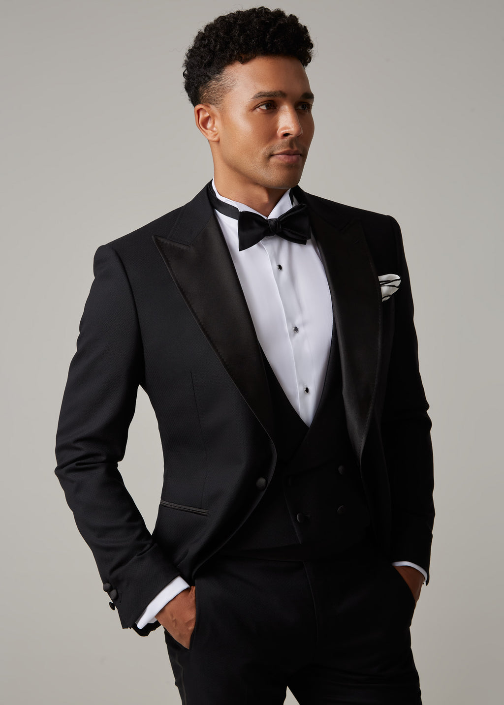 The Great Black Tuxedo jacket, three-quarter angle with model looking aside, hands in pockets