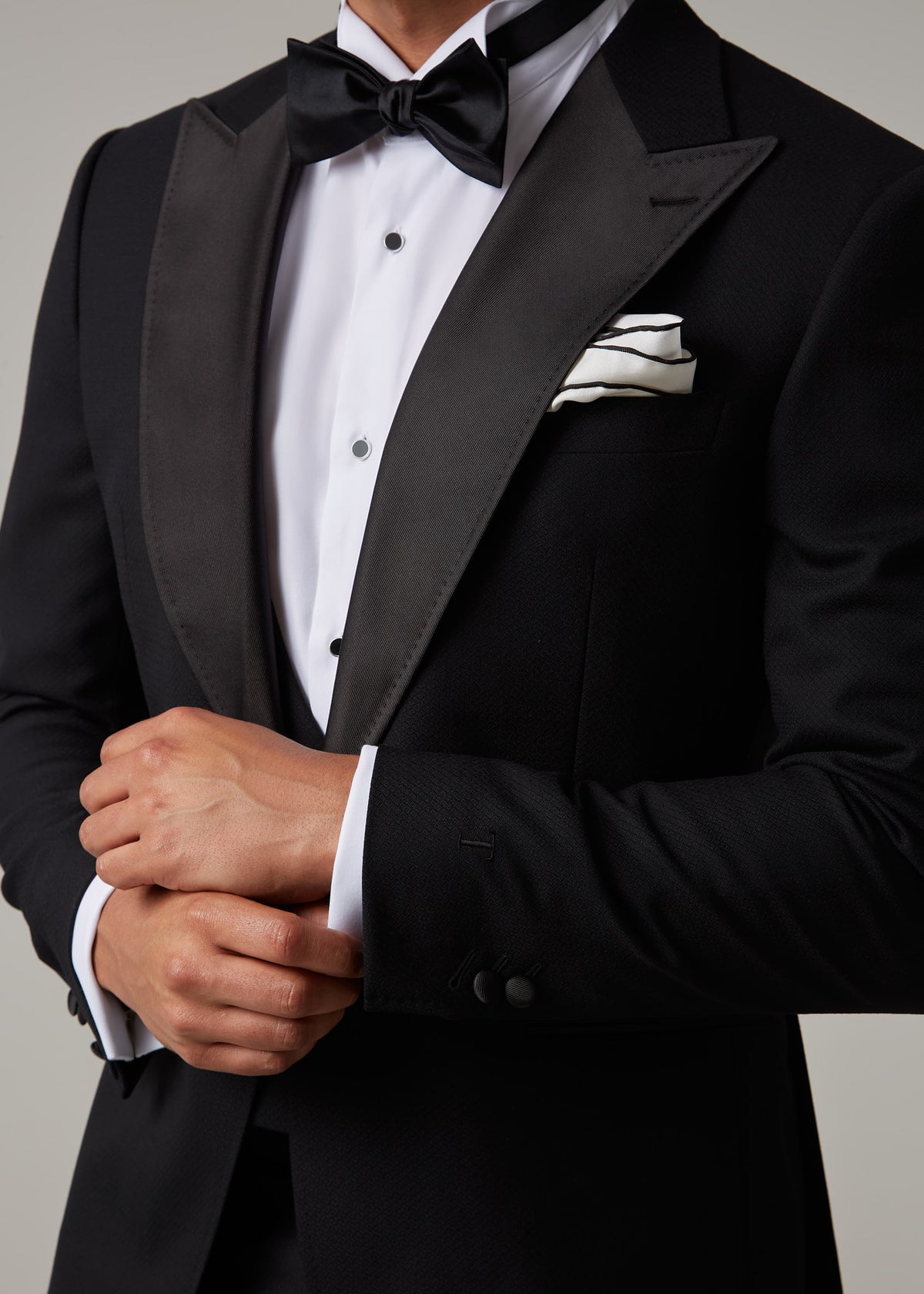 Close-up of The Great Black Tuxedo jacket cuff and sleeve with hands adjusting cuff