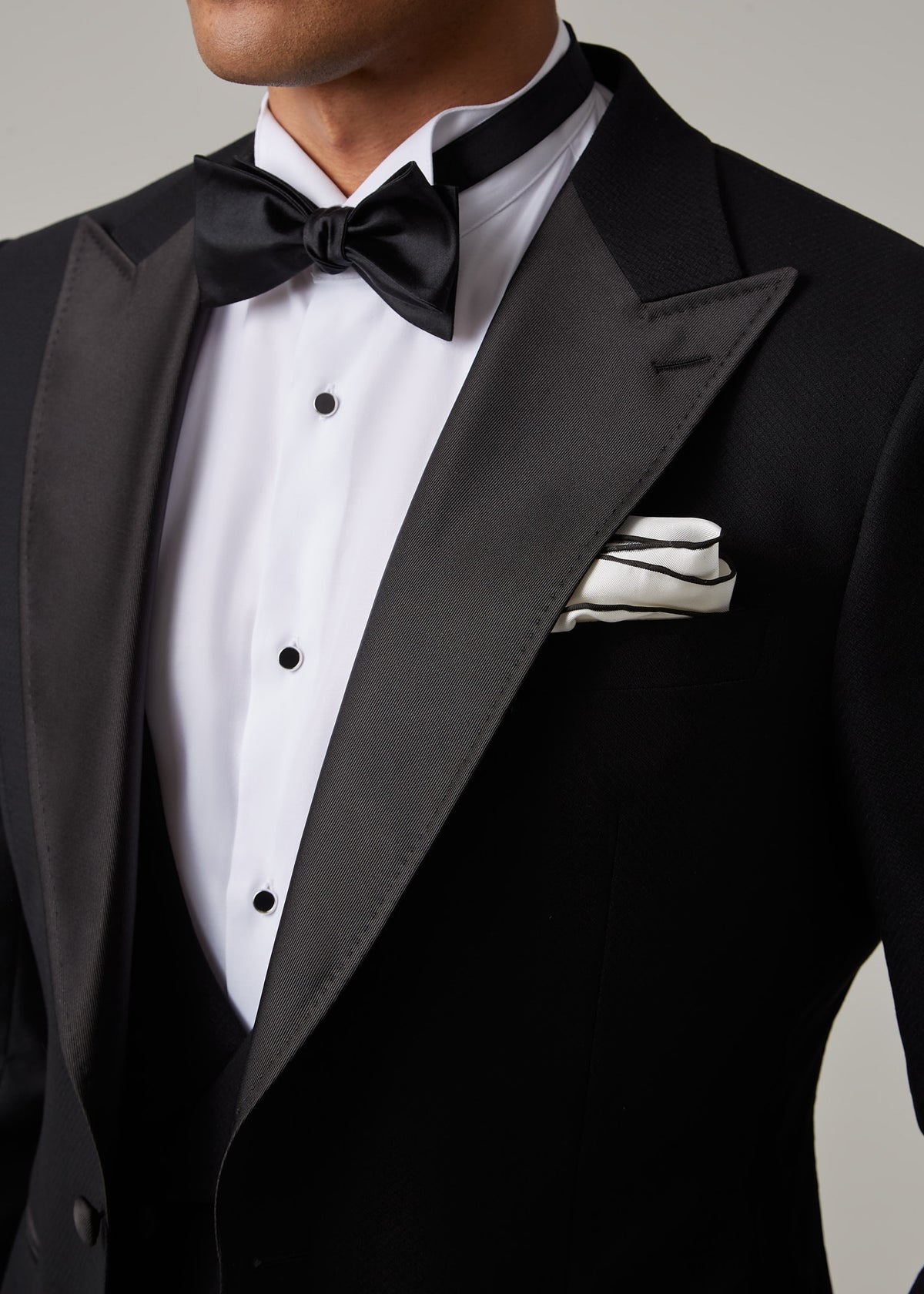 Close-up of The Great Black Tuxedo satin peak lapel, bow tie and pocket square