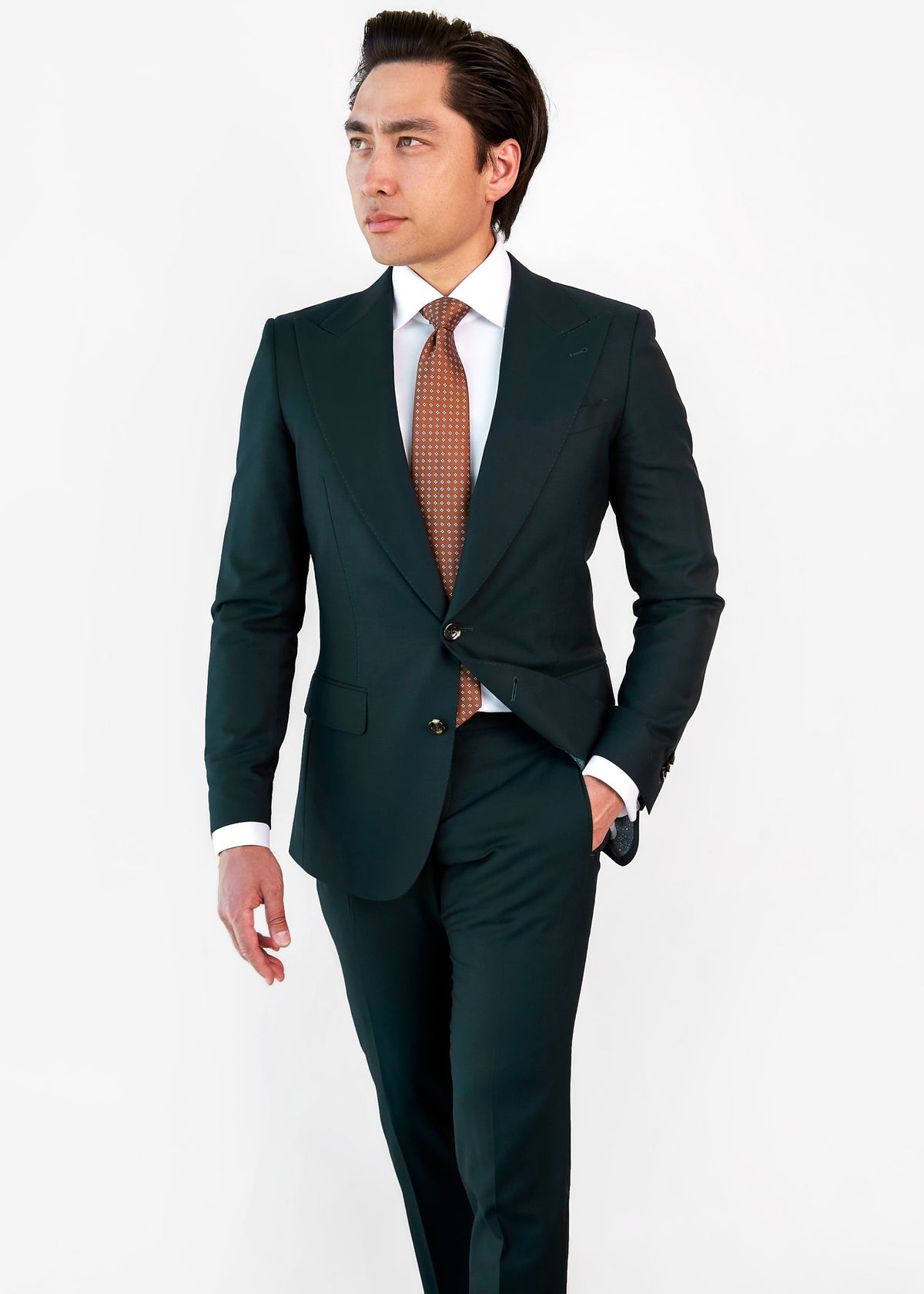 Seoul Tie in brown dotted pattern worn with a dark green suit, model looking aside