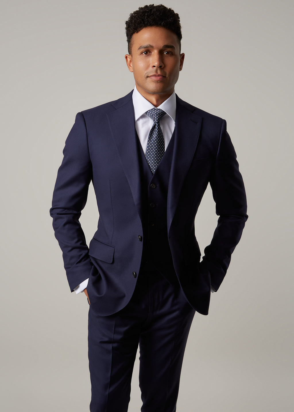 Rialto Royale Navy Suit three-piece with a patterned tie, hands tucked in pockets