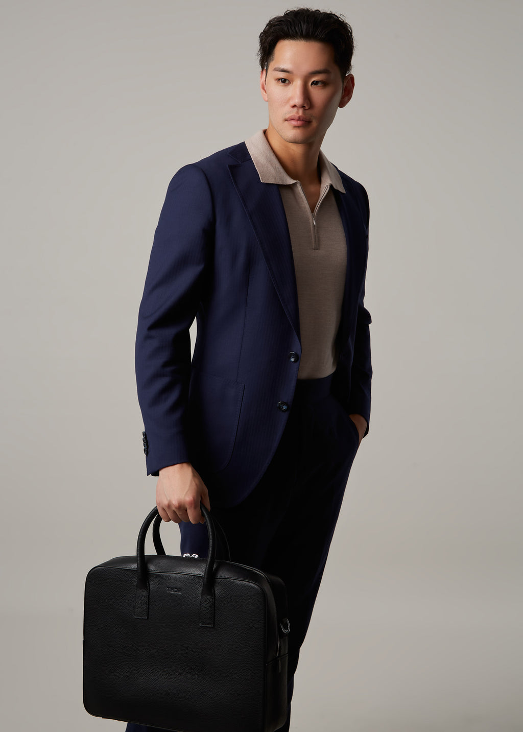 Timothy briefcase carried by a model wearing a navy blazer, full-length shot