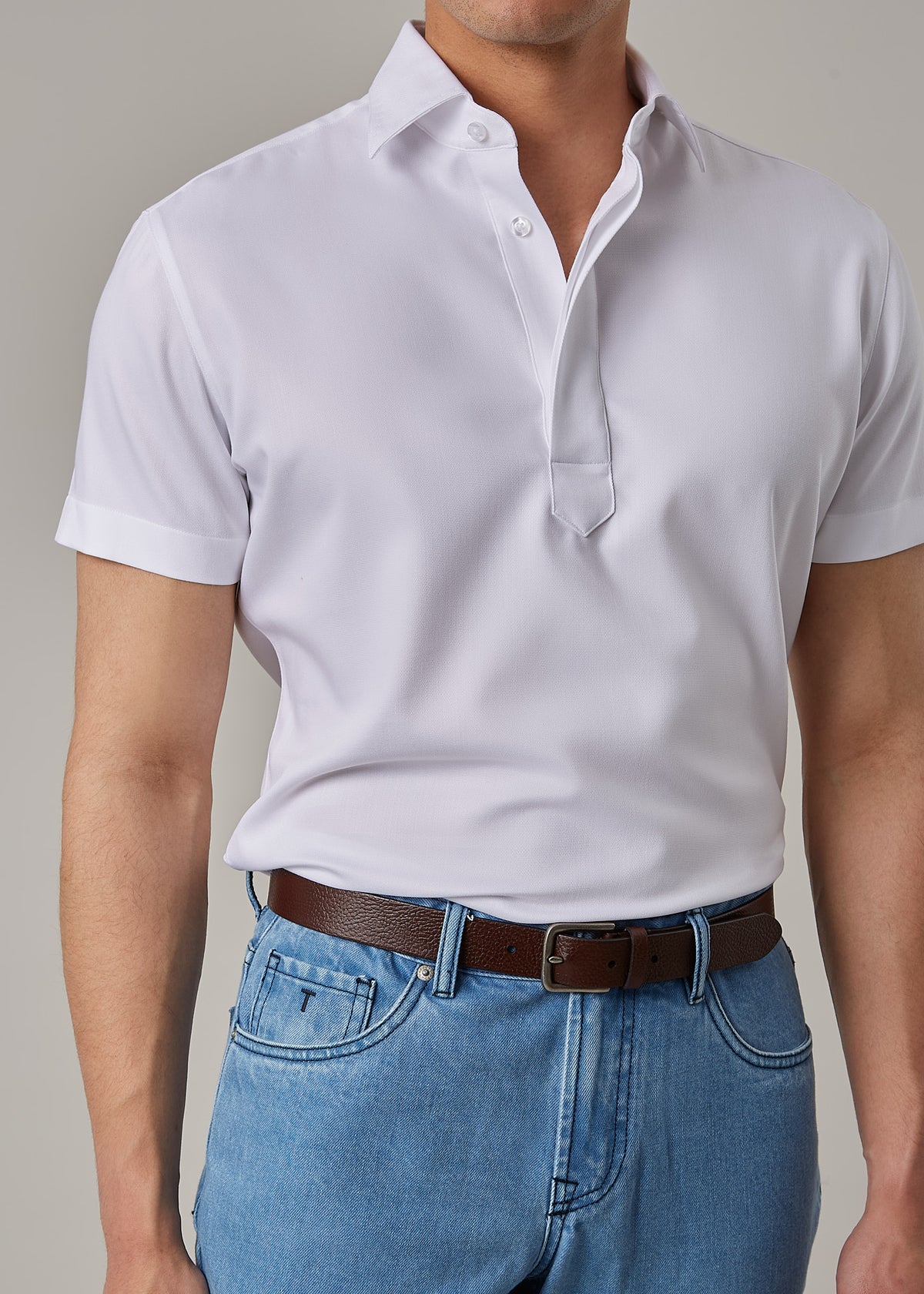 White Short Sleeve Popover Shirt, close-up chest view on a model with jeans and belt