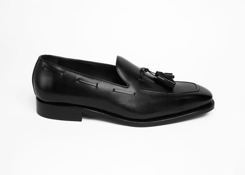 Black box calf tassel loafer, single shoe side profile on a plain background