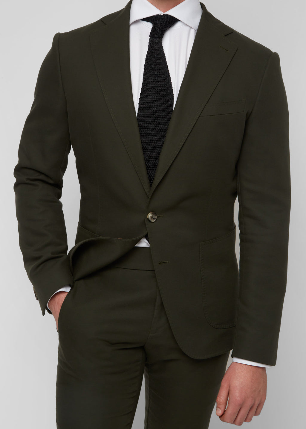 Greenwich Village Olive Suit close-up on a model with hand in pocket and knit tie