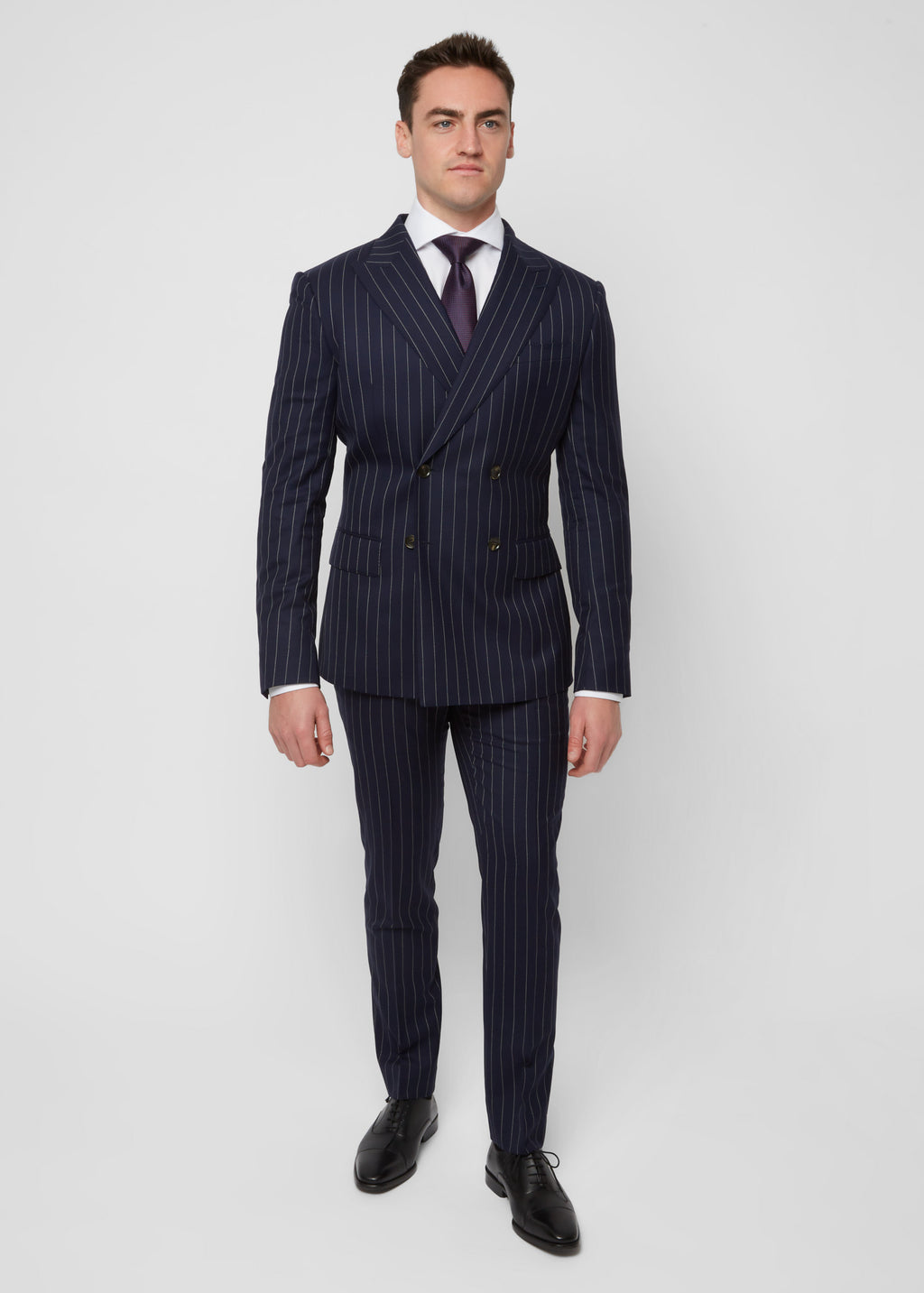 Savile Row Navy Pinstripe Suit worn with a rust tie, front view, hands in pockets