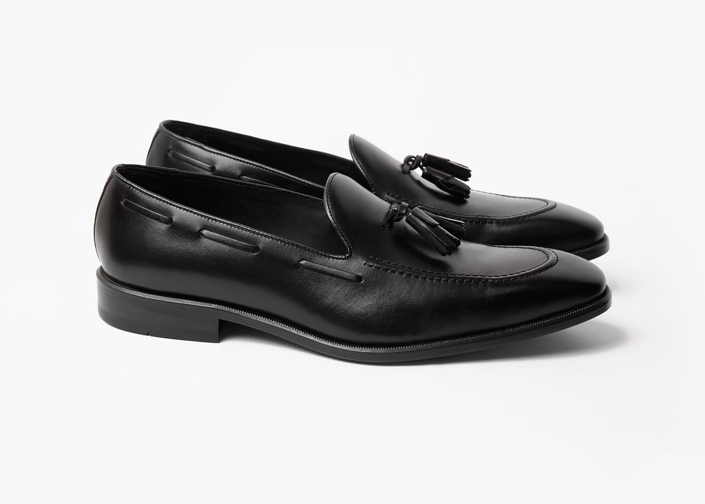 Pair of black box calf tassel loafers shown at an angled three-quarter view