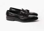 Pair of black box calf tassel loafers shown at an angled three-quarter view