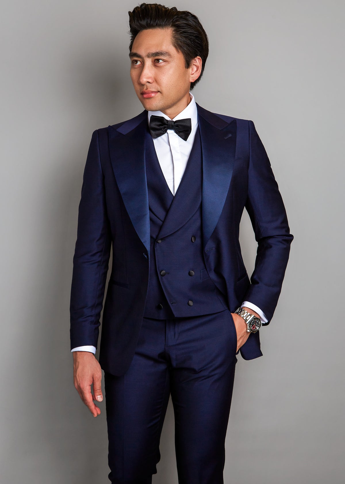 Cannes Navy Tuxedo, a model looking aside shows the satin lapel and waistcoat