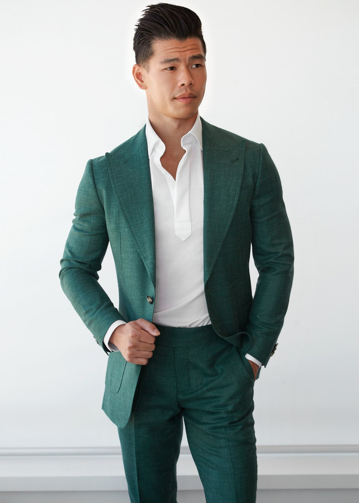Ivory popover shirt worn under an open green suit jacket on a model