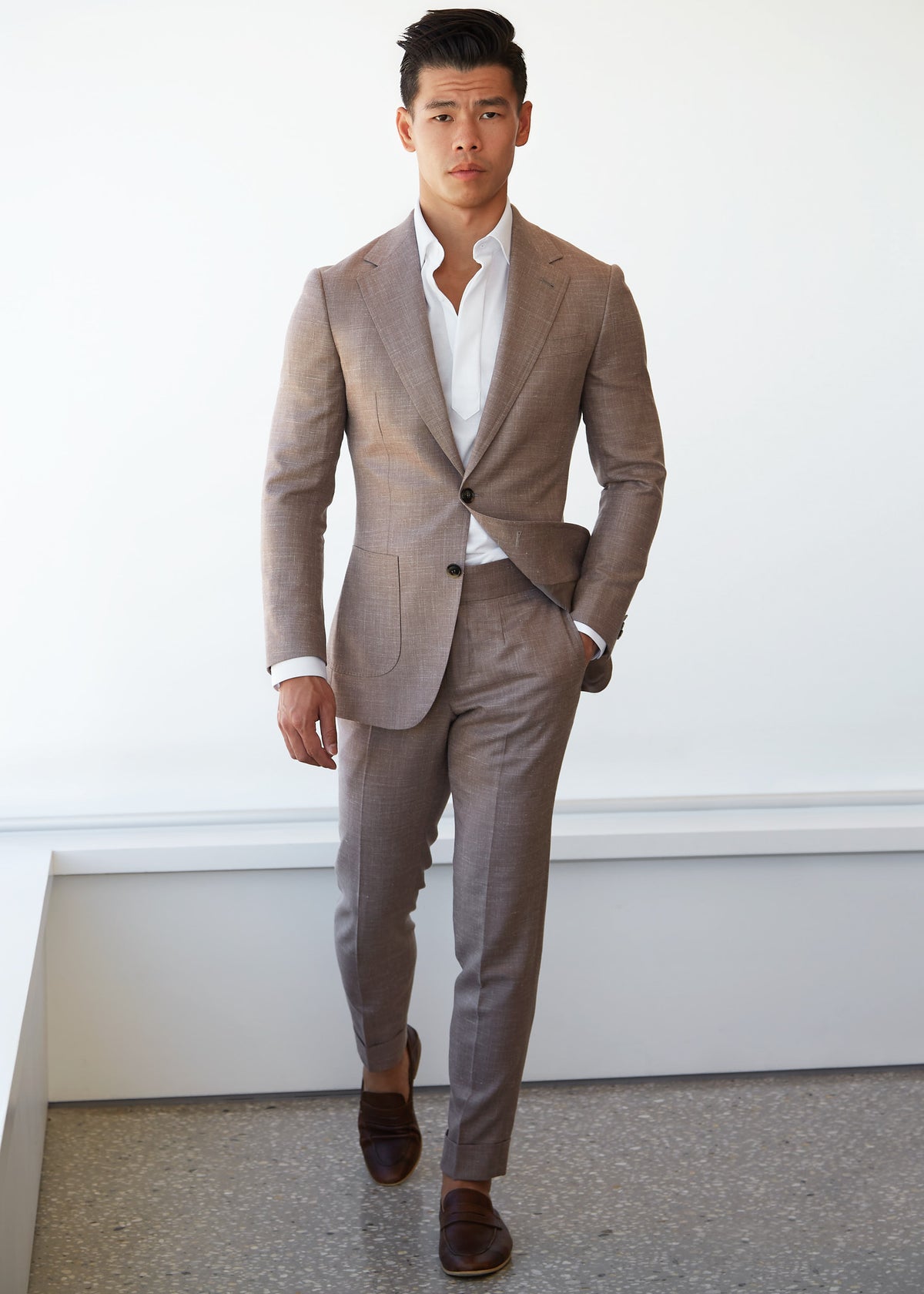 Ivory popover shirt worn under a tan suit on a model, full-length walking shot