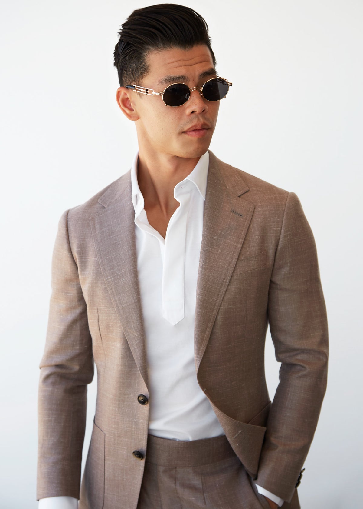 Ivory popover shirt worn under a tan suit jacket, model wearing sunglasses