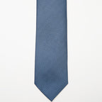 Tulum Tie in a blue pattern laid flat on a plain background