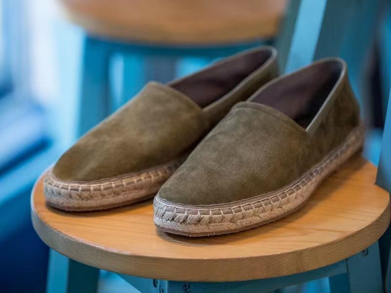 Aries Olive Handcrafted Woven Fisherman Shoes, pair resting on a wooden stool
