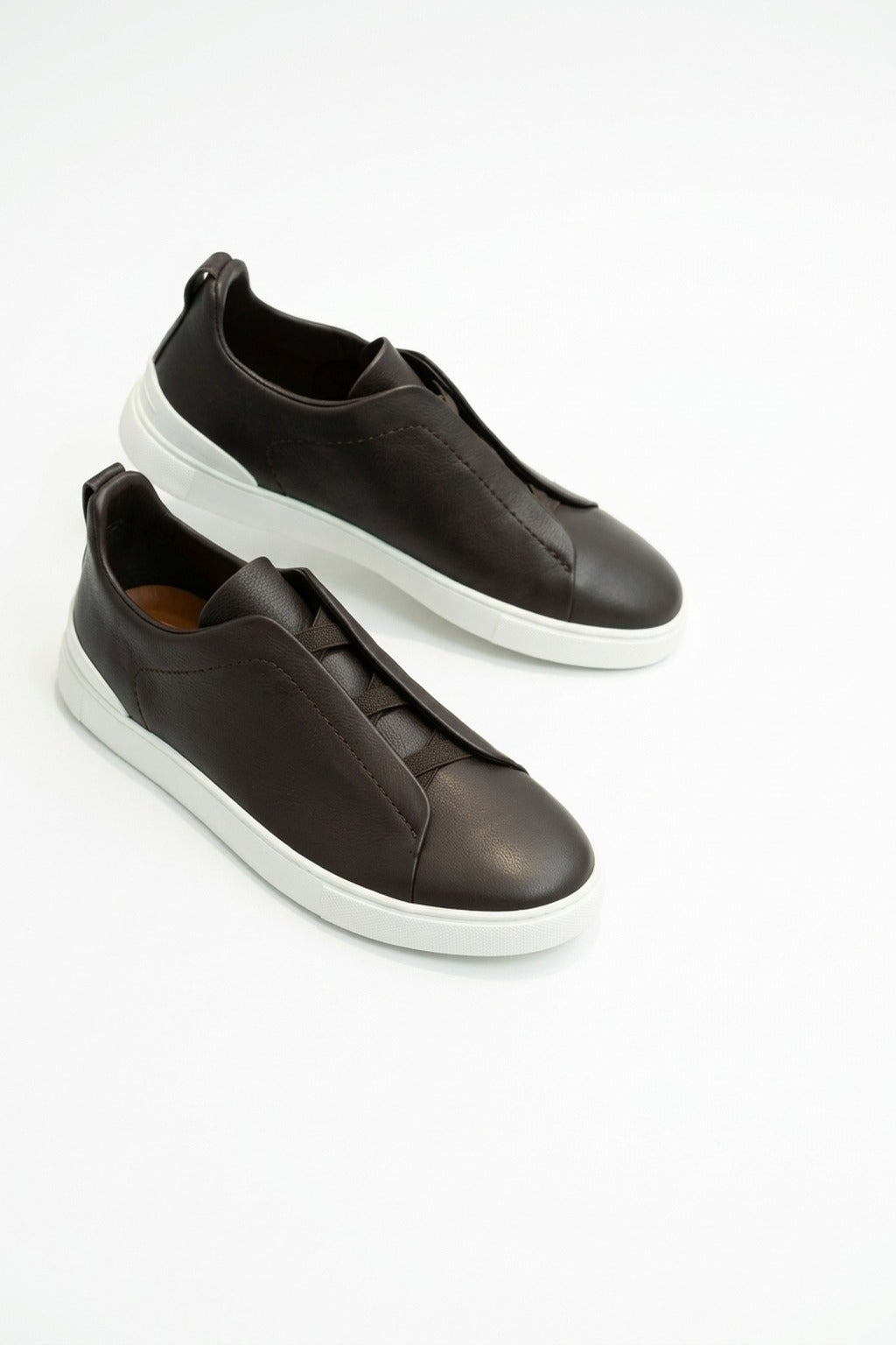 The Capri Dark Brown Leather Slip-On Sneaker, pair in the studio