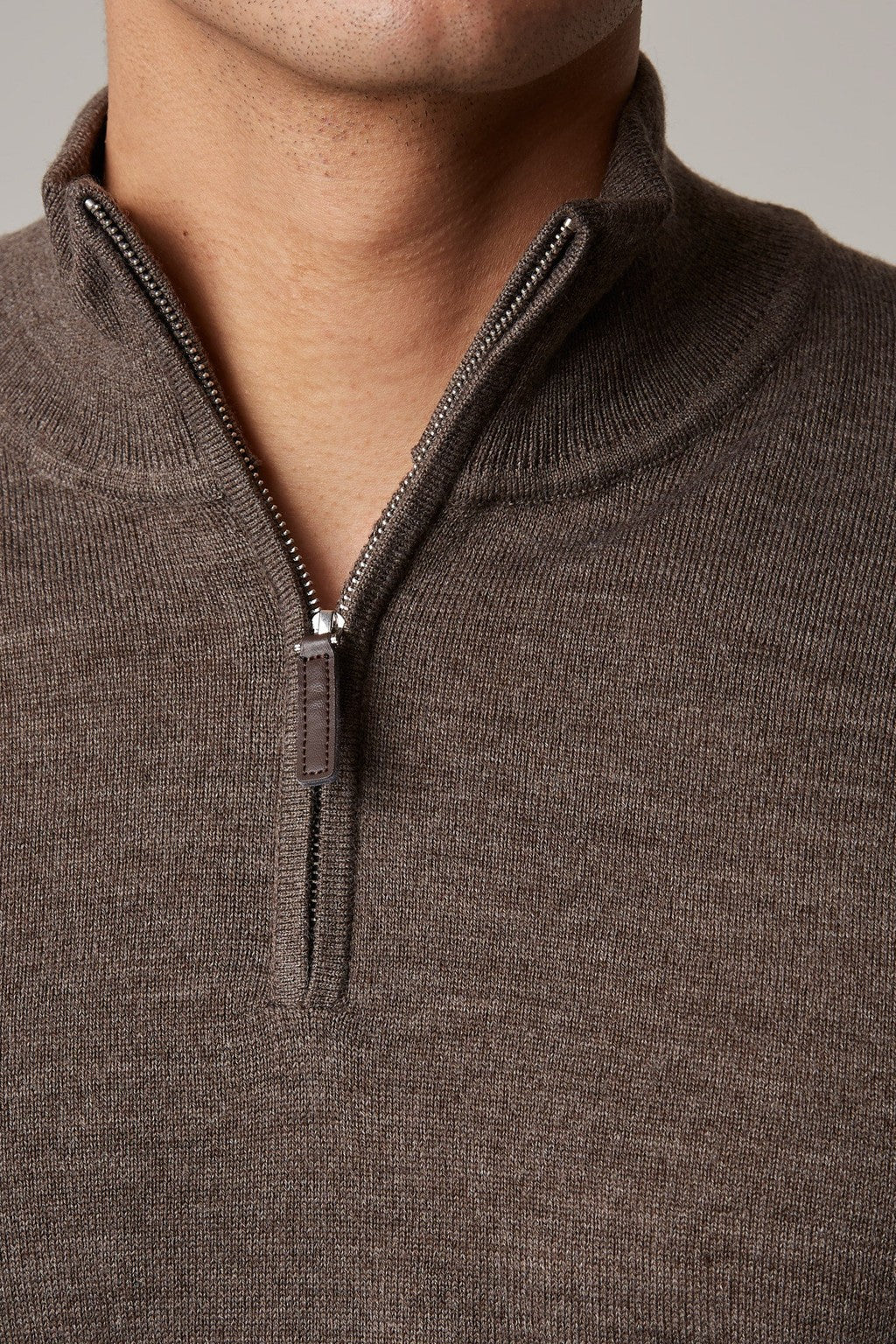Close-up of the brown Cosmo quarter-zip jumper's collar and zip pull