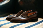 The Morton Brown Penny Loafer pair in side profile on a striped bench