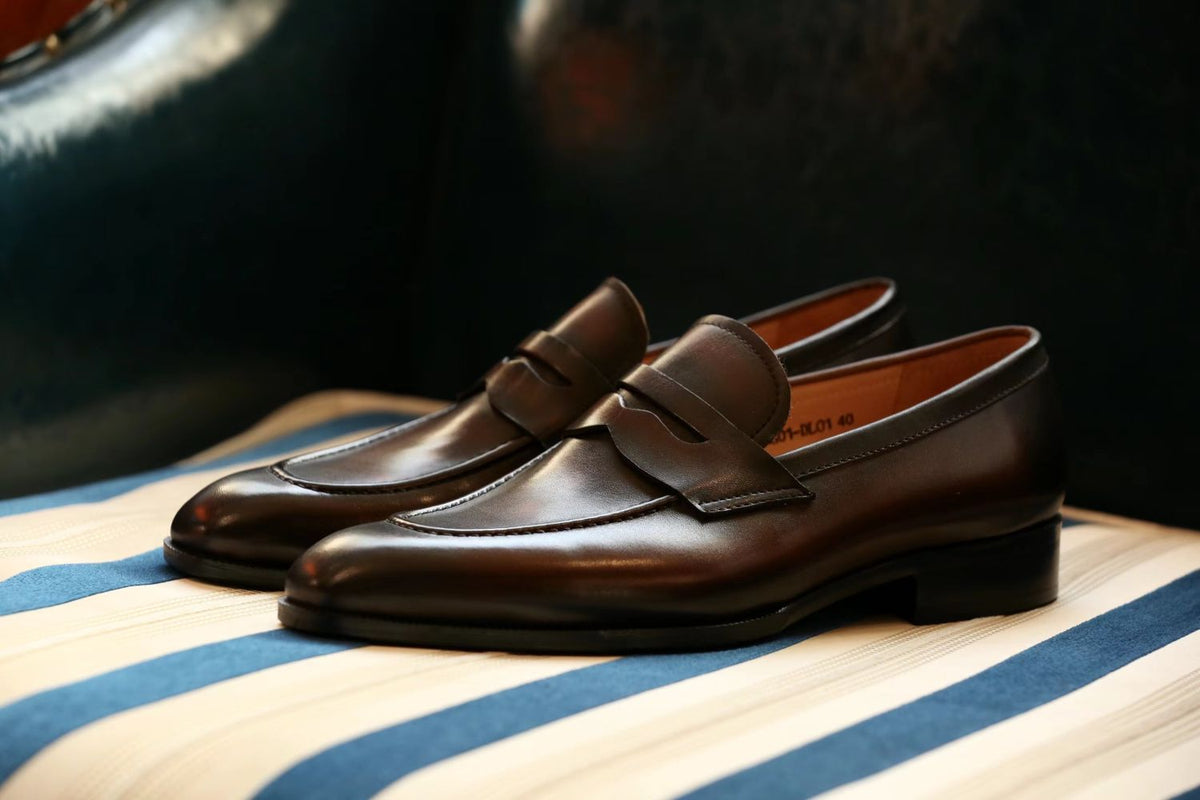 The Morton Brown Penny Loafer pair in side profile on a striped bench