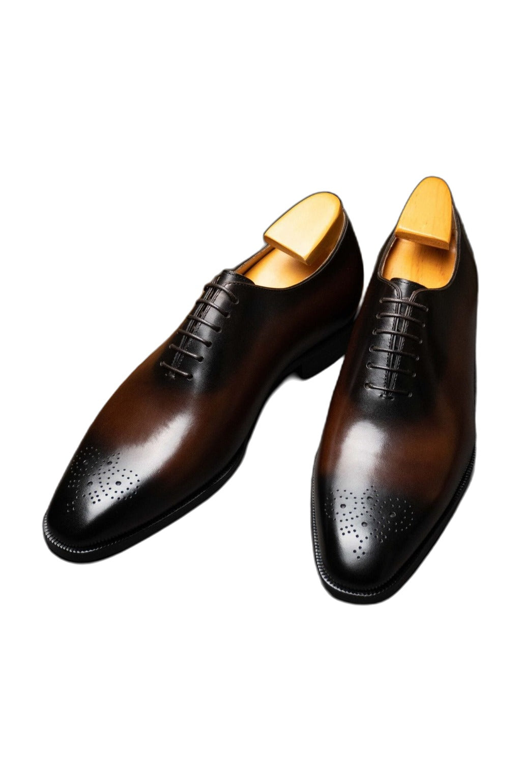 The Dino Wholecut Brogue Brown Oxfords with Hidden Height Lift, pair on shoe trees, angled view on white