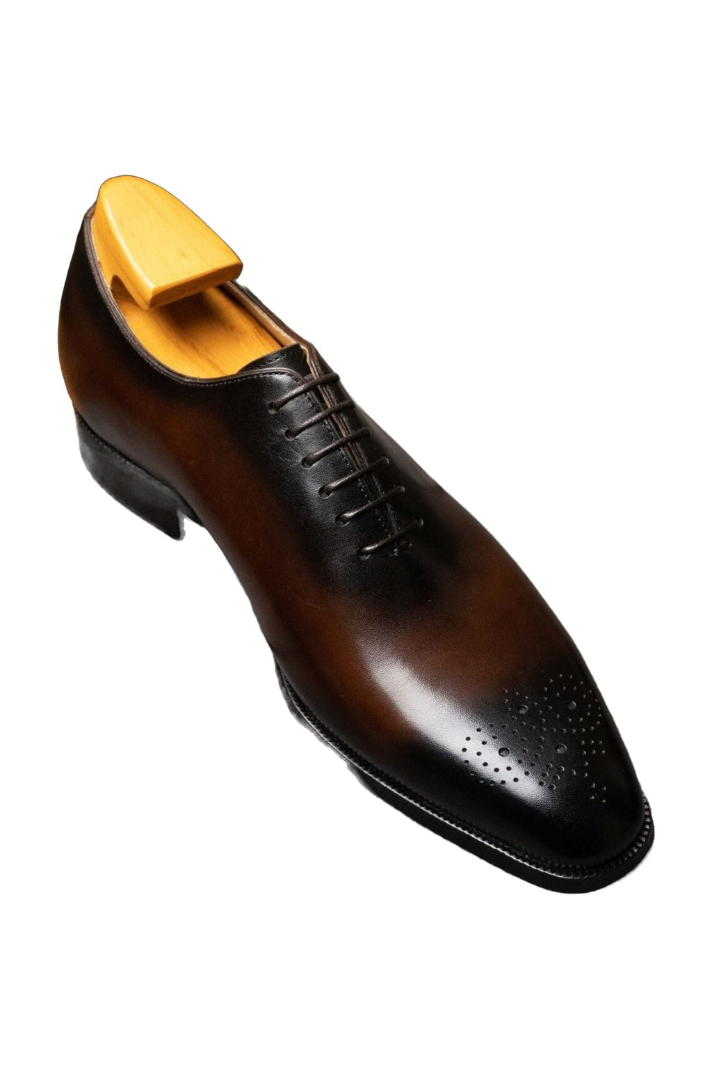 The Dino Wholecut Brogue Brown Oxford on a shoe tree, showing the burnished toe, on white