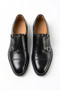 The Friar Black Leather Double Monk pair on white, top-down view of the silver buckles and punched cap toe