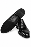 The Haider Black Patent Leather Oxford pair on white, one shoe turned to show the sole