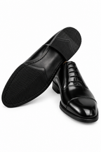 The Haider Black Patent Leather Oxford pair on white, one shoe turned to show the sole