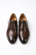 The Konbanwa Square-Toe Triple-Stitched Brown Oxford pair on white, top-down view of the burnished cap toe