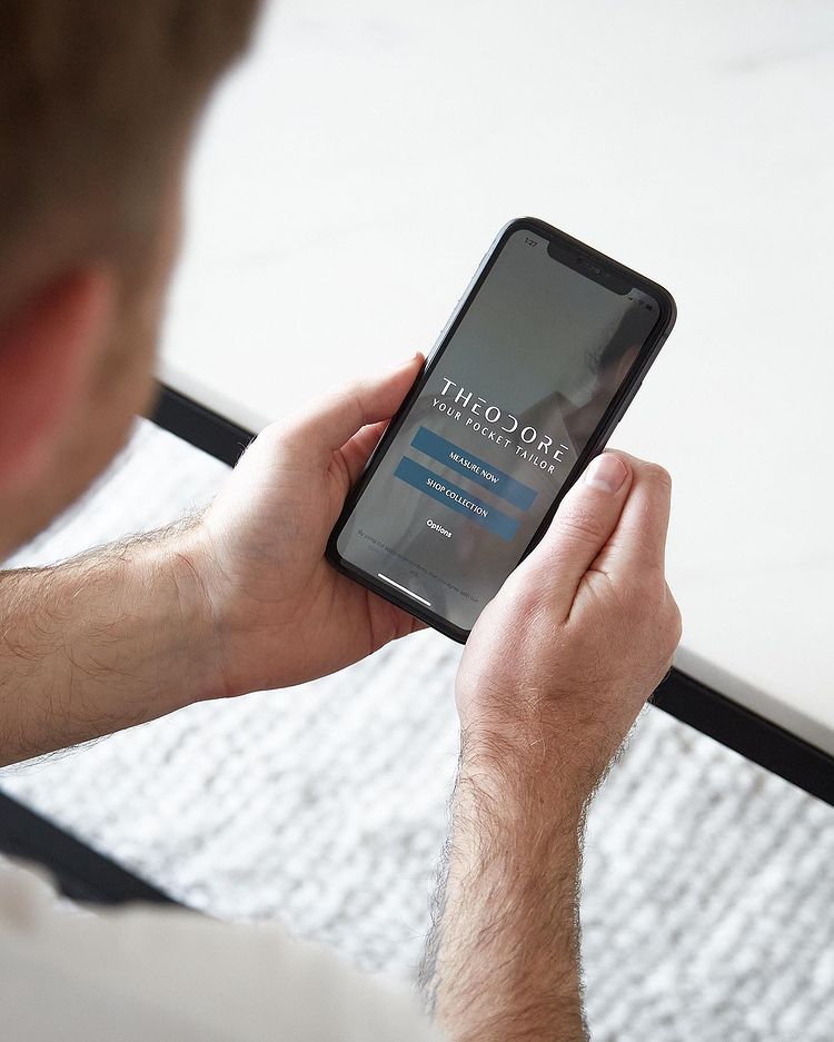 A client holding his phone with the THDR Pocket Tailor app open
